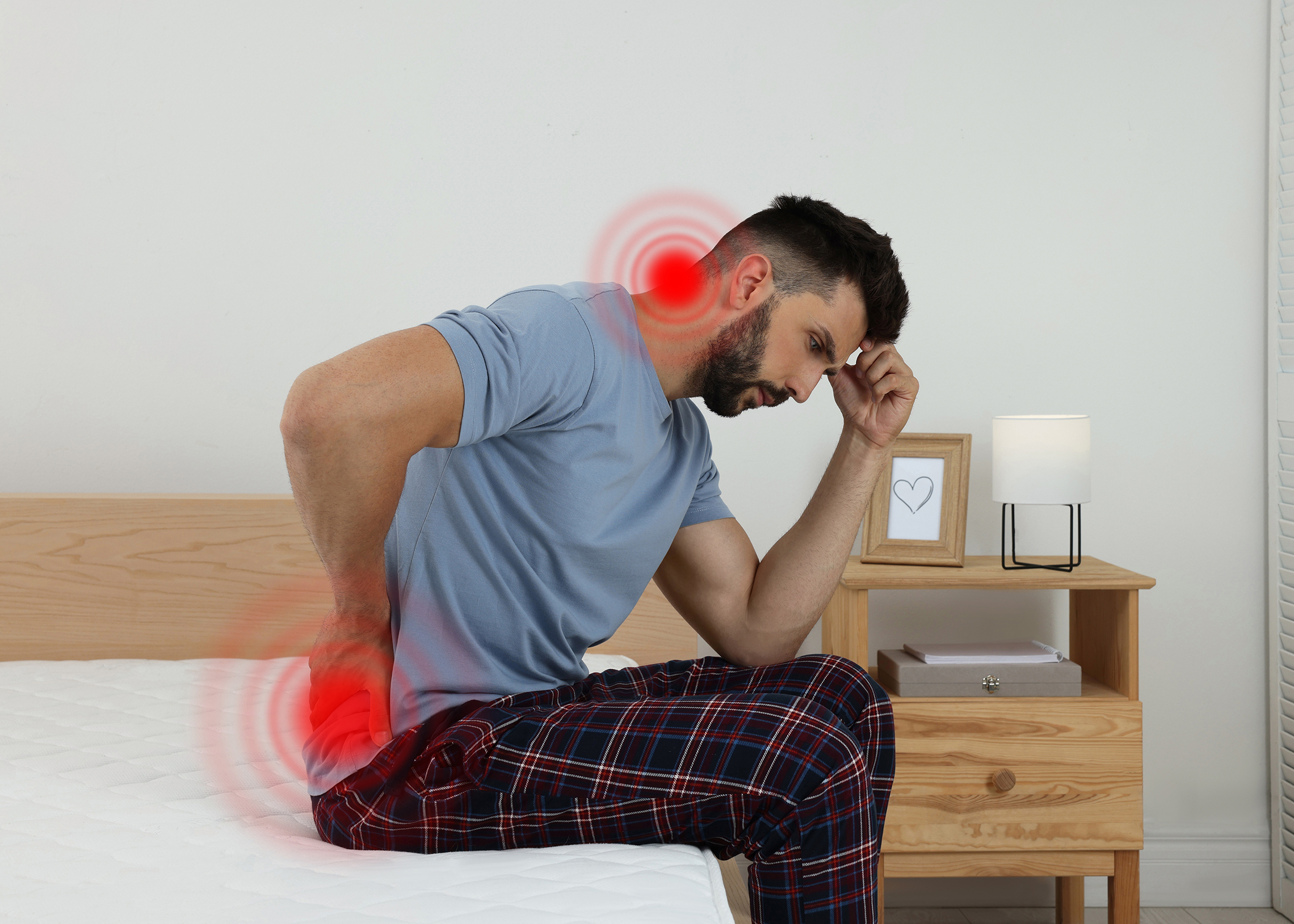 Man suffering from back pain after sleeping on uncomfortable mattress at home