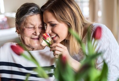 Older woman and granddaughter smelling tulips representing smell loss