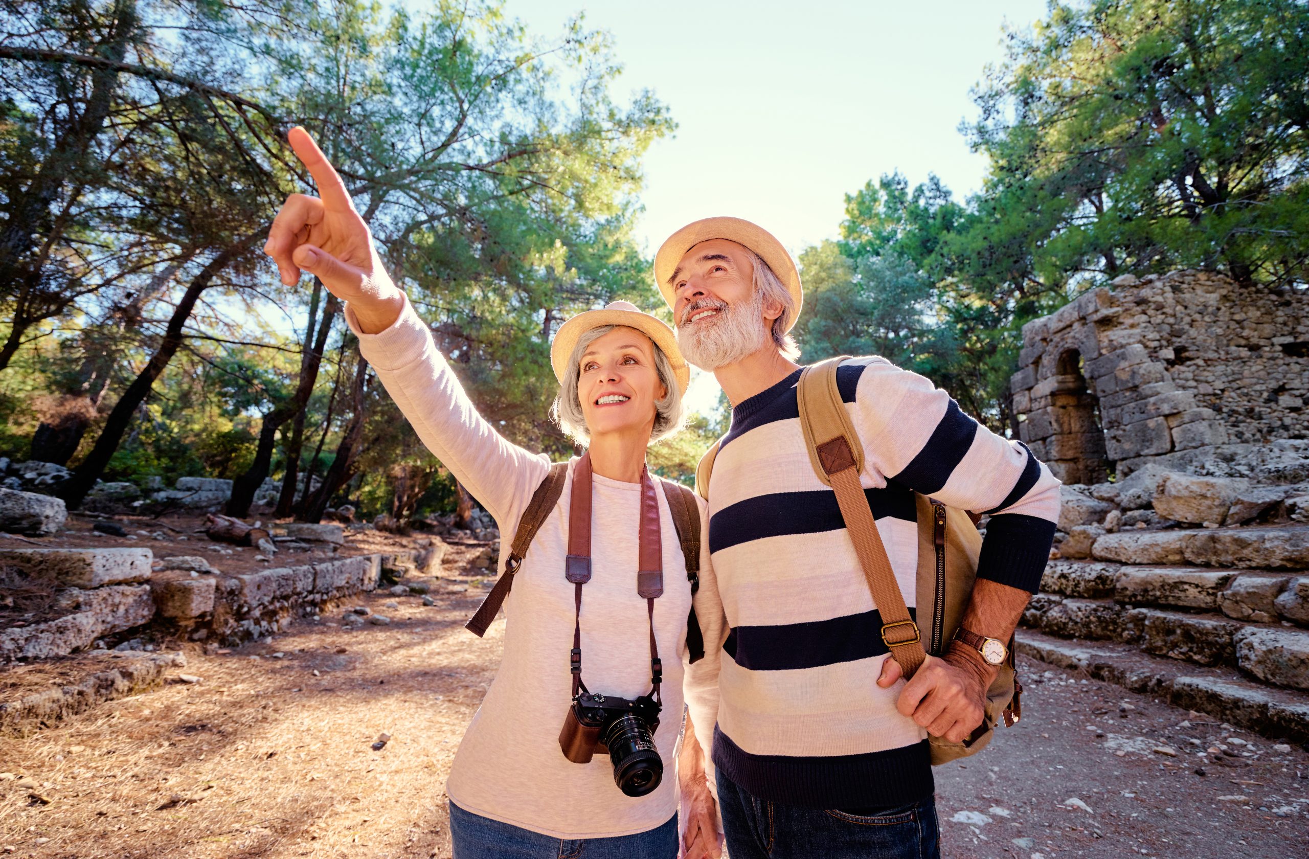 Couple on a hike carrying camera and bag pointing at things and smiling. Represents the power of experiences and their neurological effects on the brain.